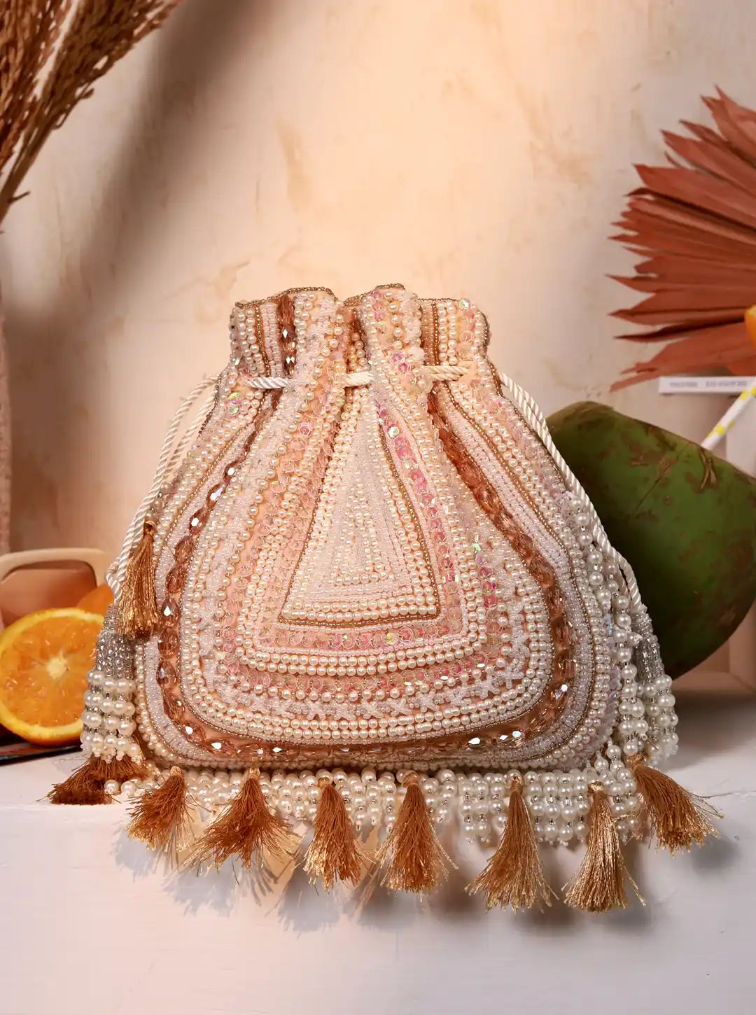 Decorative handbag with beaded details and tassels on a neutral background