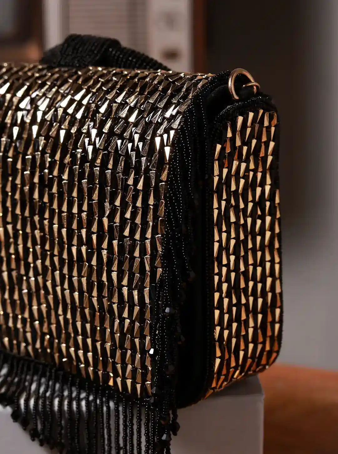 Close-up of a woven handbag with black fringe on a blurred background