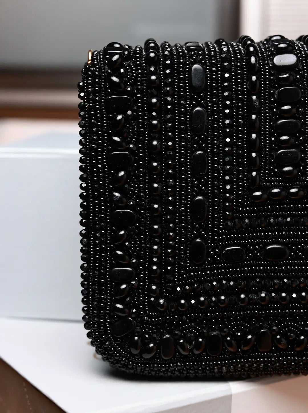 Black beaded clutch bag on a white surface