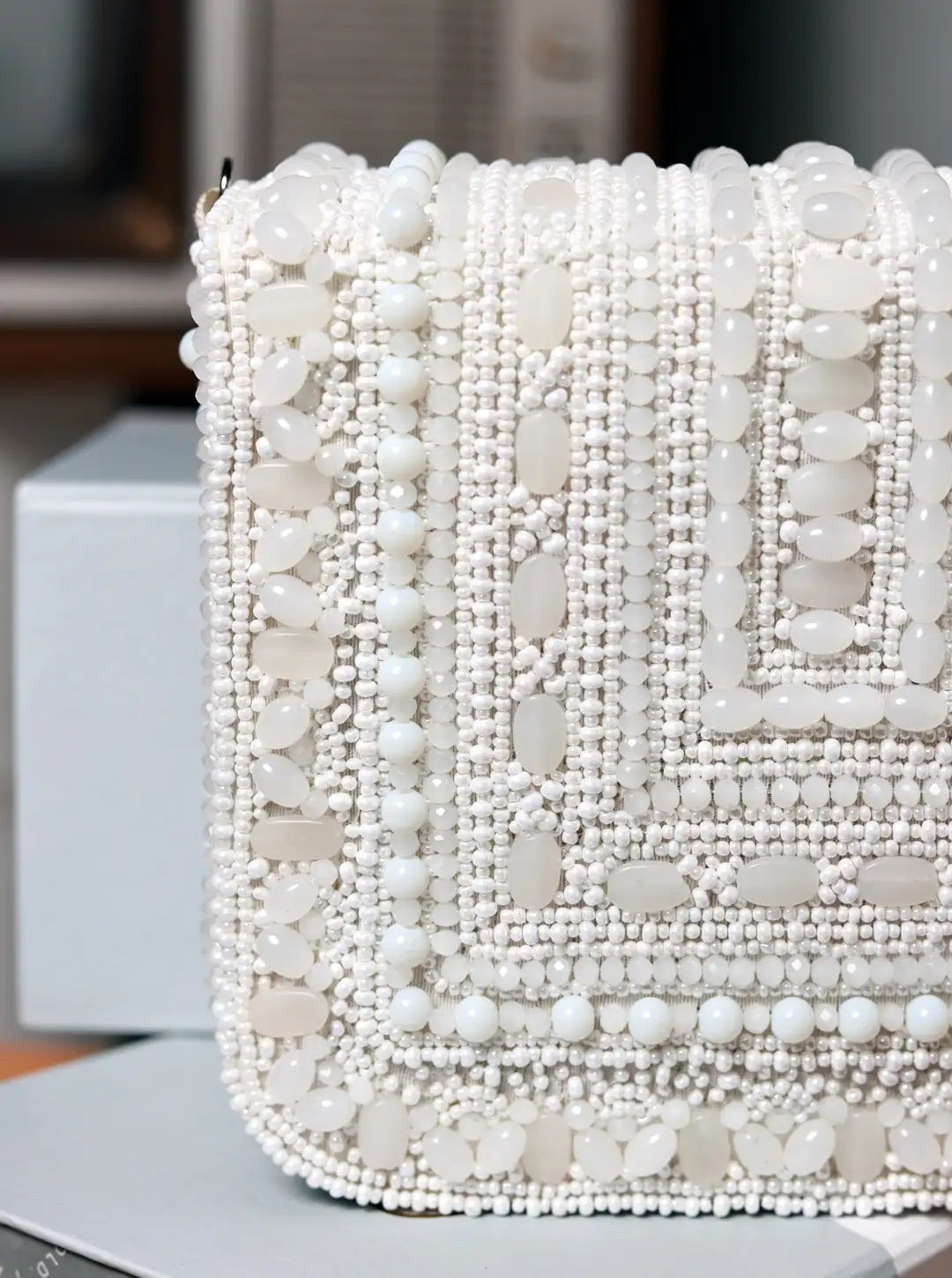Close-up of a white beaded clutch bag on a blurred background