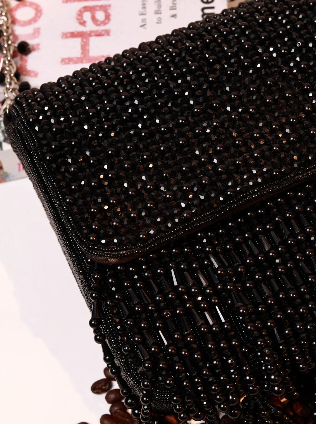 Close-up of a black beaded clutch bag with a blurred background