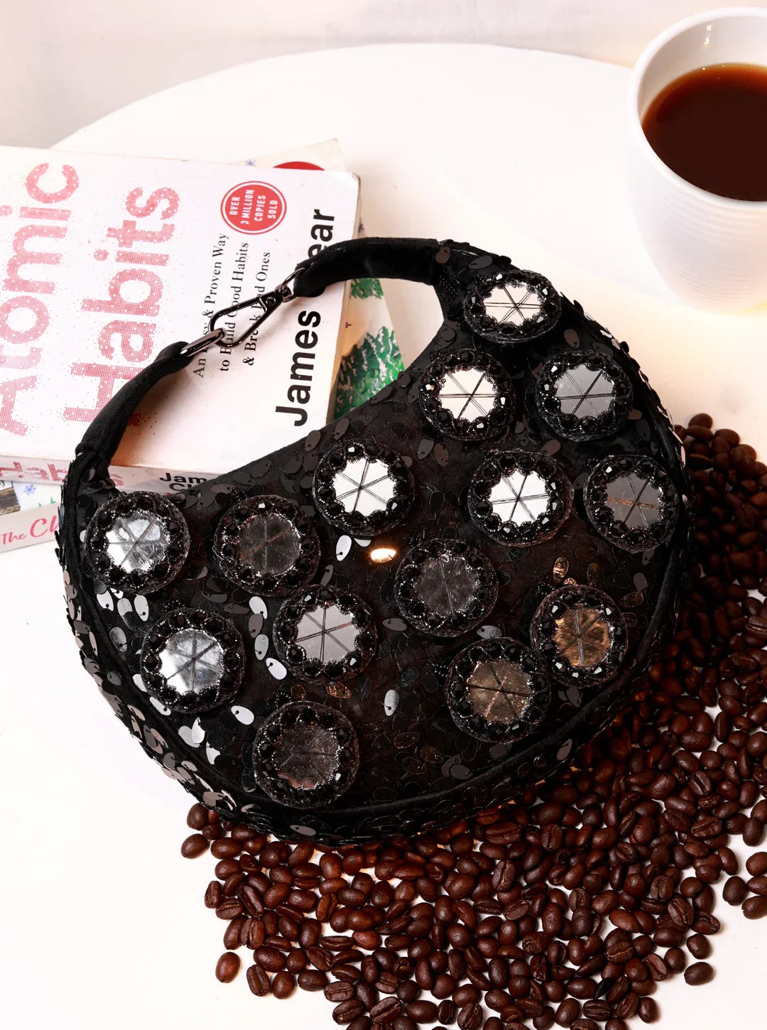 Black beaded handbag on a surface with coffee beans and a cup of coffee.