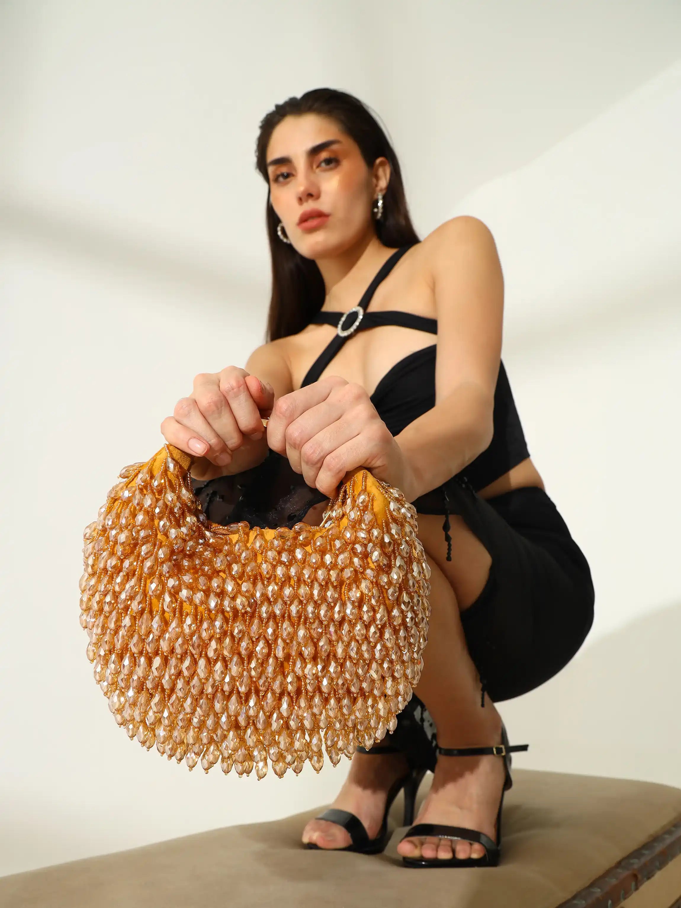 Woman holding a beaded handbag against a plain background
