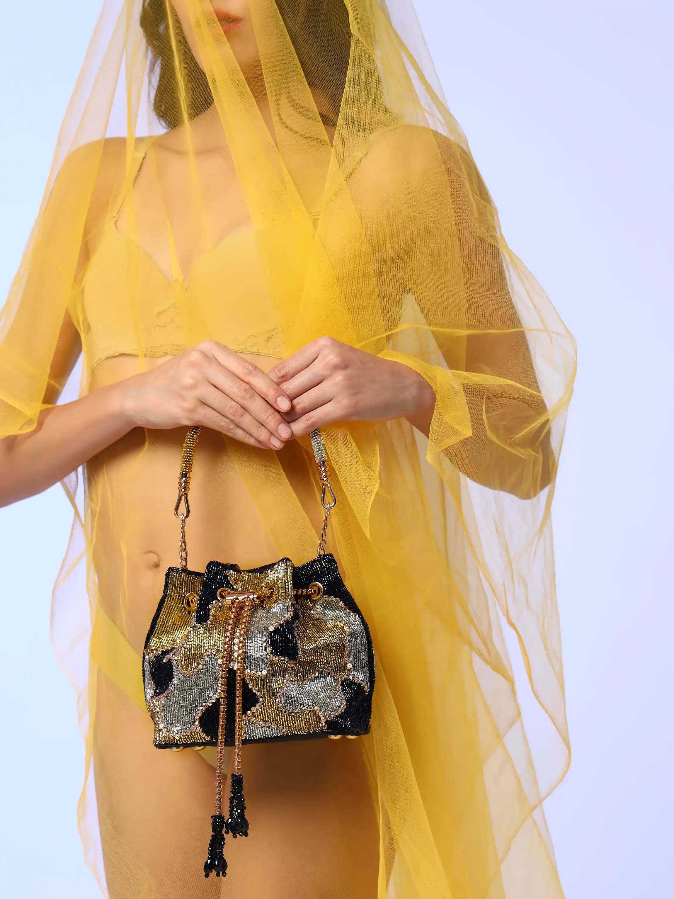 Person holding a decorative handbag with a sheer yellow fabric overlay