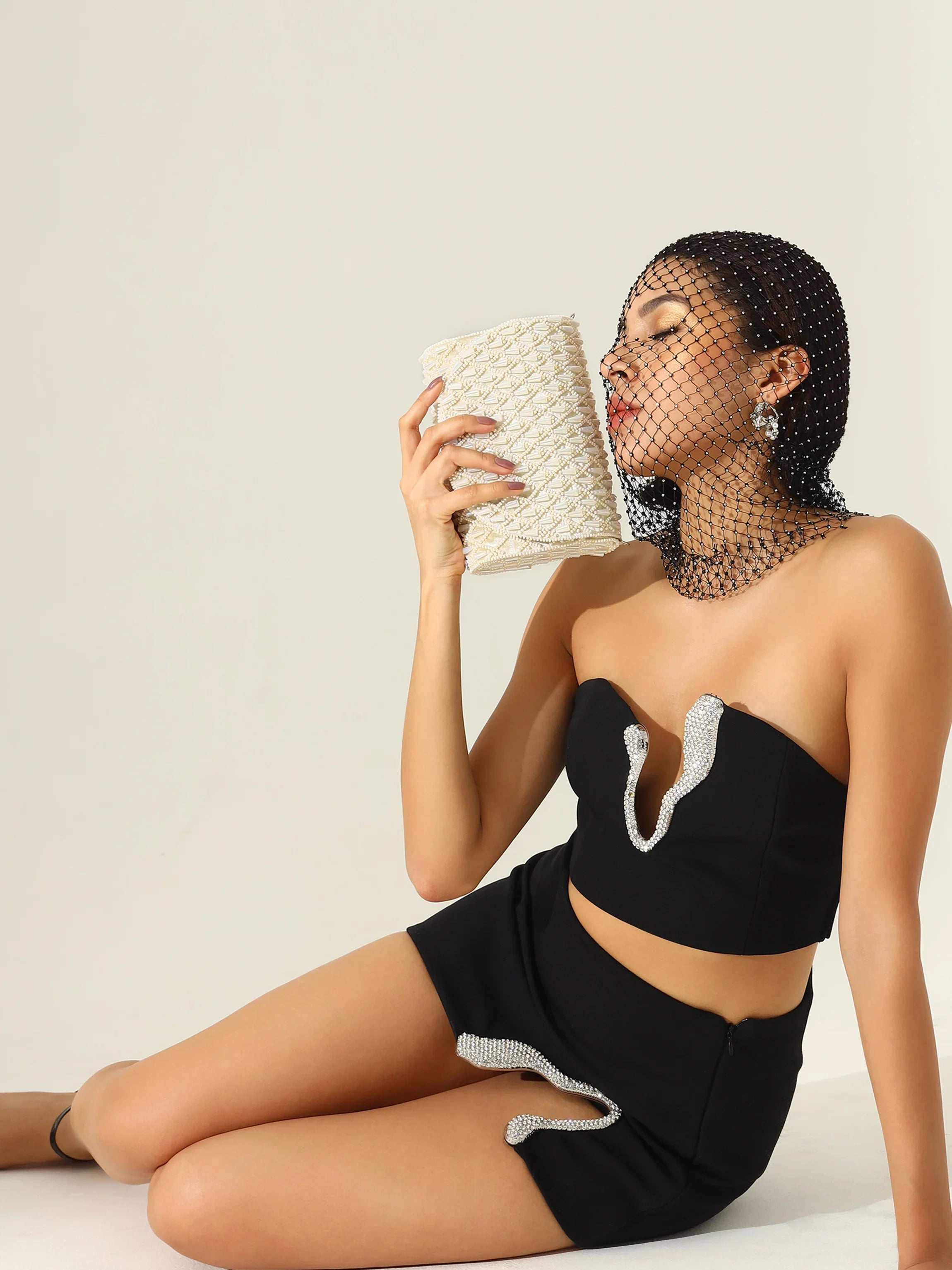 Woman in a black outfit holding a woven basket against a plain background