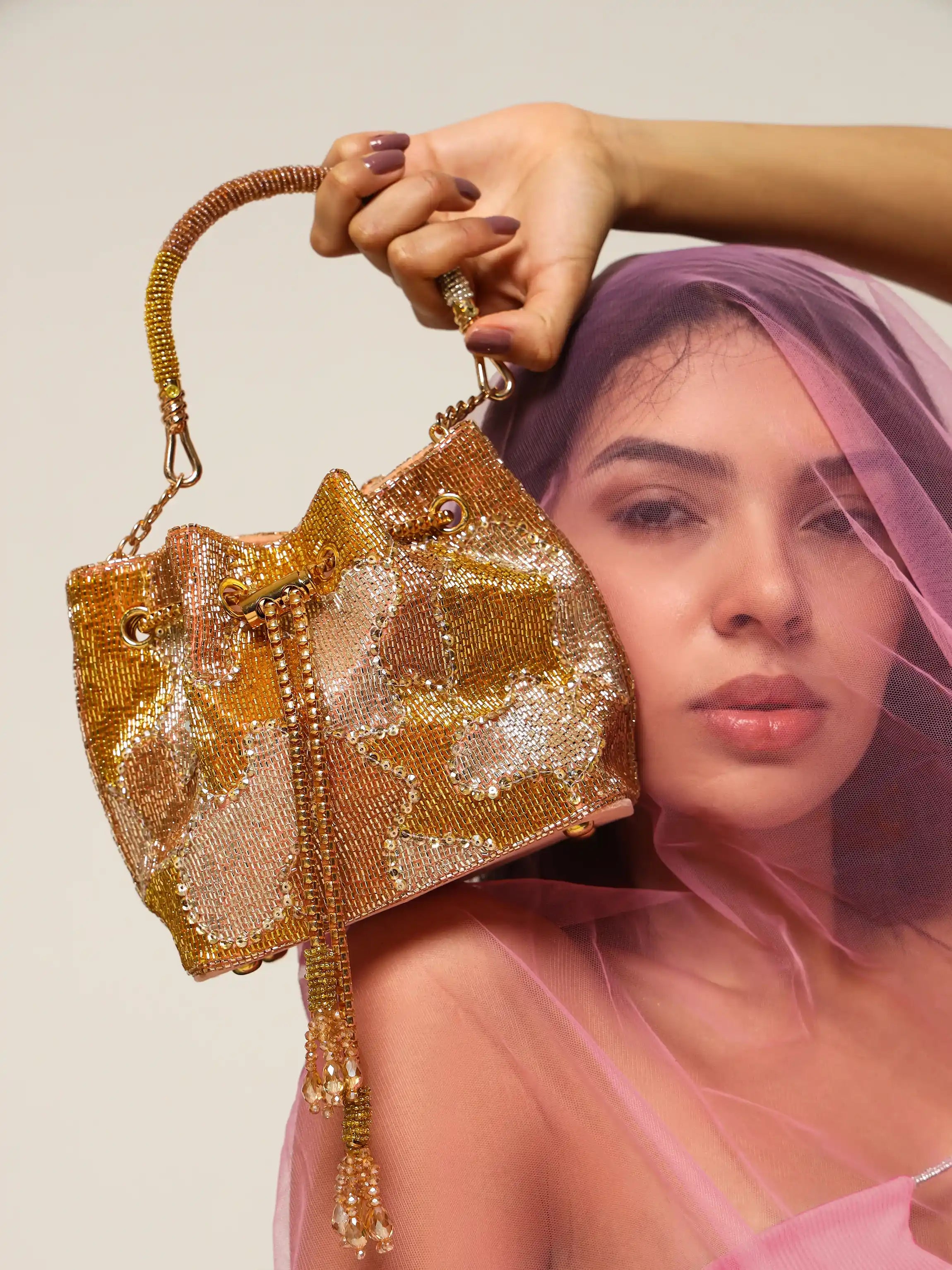 Woman holding a gold beaded handbag against a neutral background