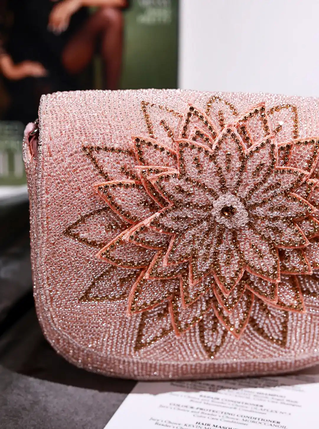 Pink handbag with floral beaded design on a blurred background