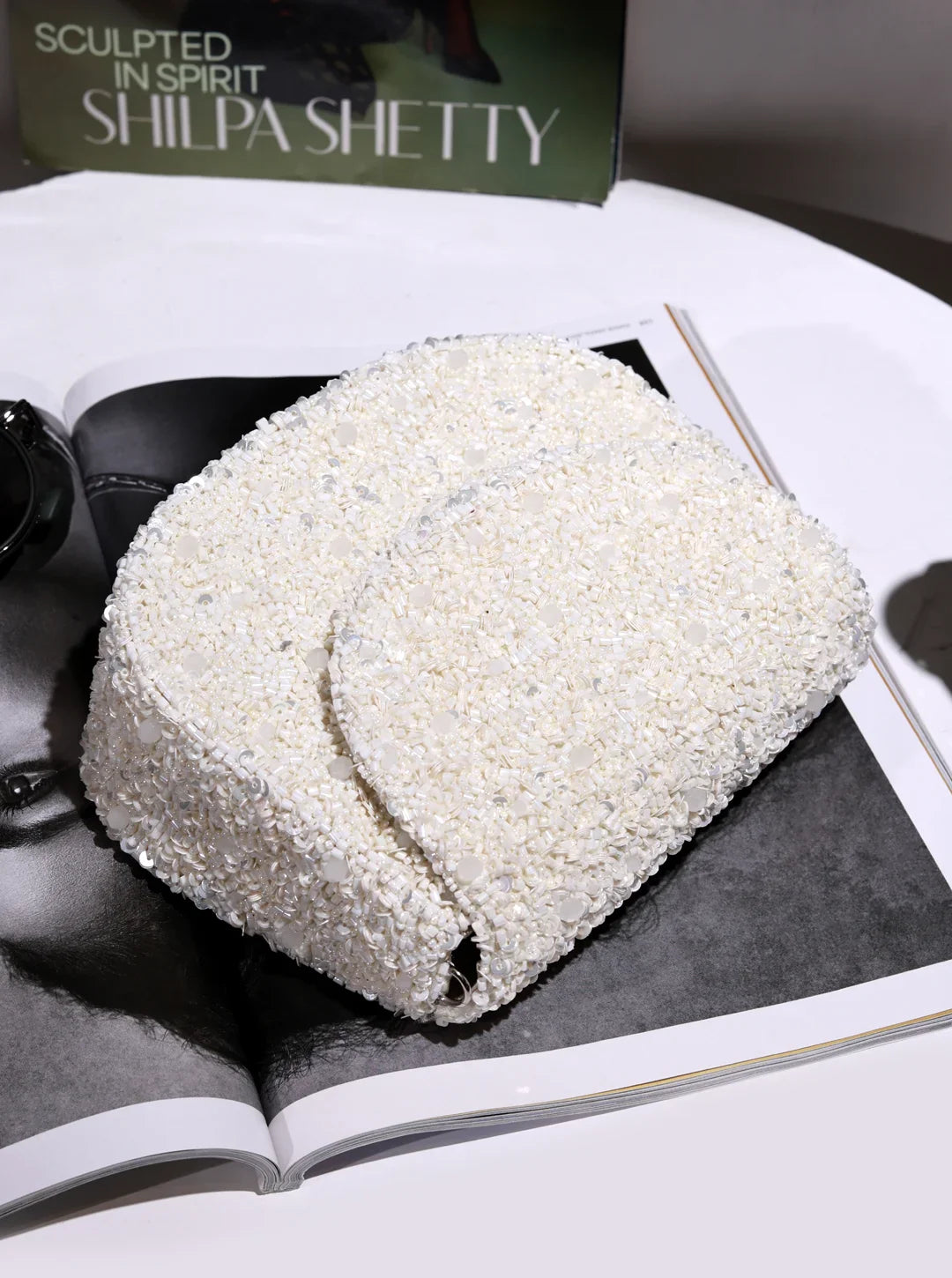 White textured object on a magazine with 'Sculpted in Spirit Shilpa Shetty' text.