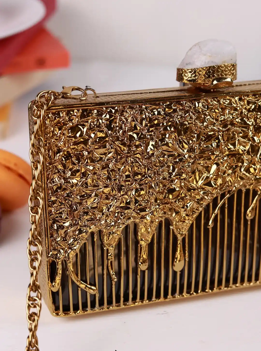 Gold clutch with intricate design on a white background