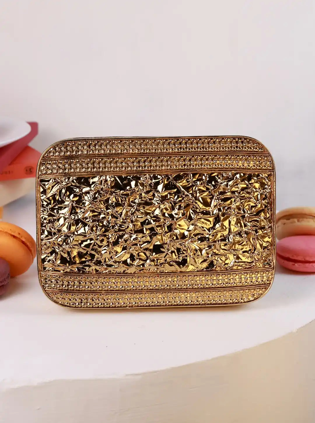 Gold clutch bag with intricate design on a white background
