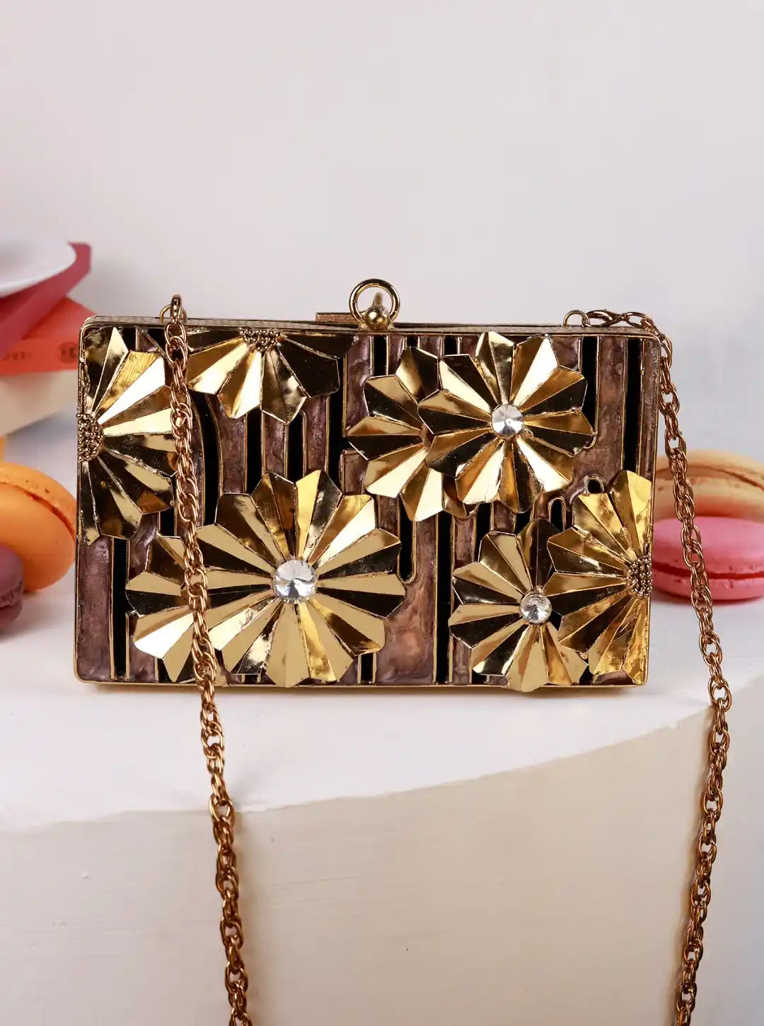 Gold clutch bag with floral designs on a white surface