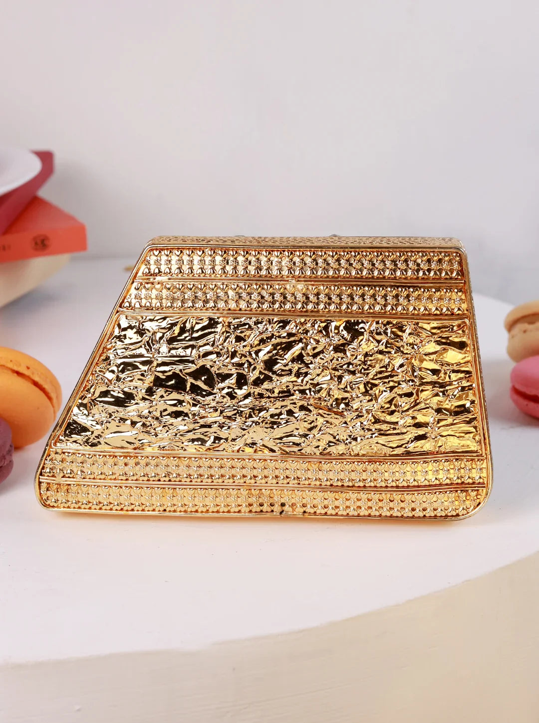 Gold clutch bag on a white surface with decorative elements