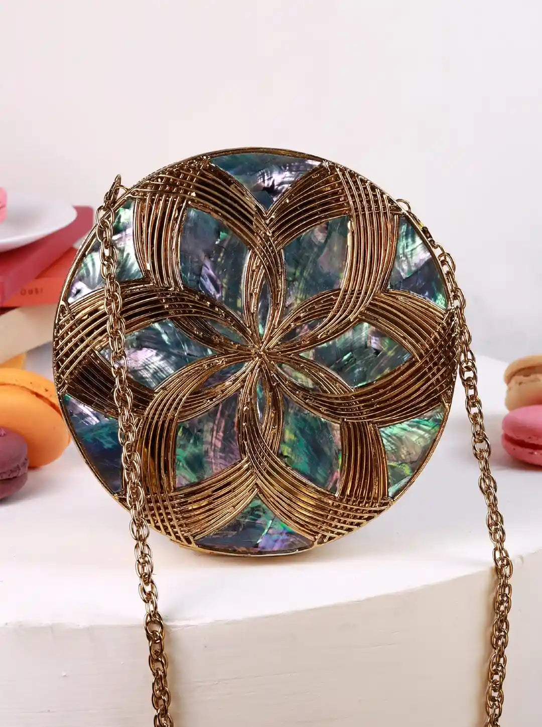 Round handbag with floral pattern and gold chain strap on a white surface