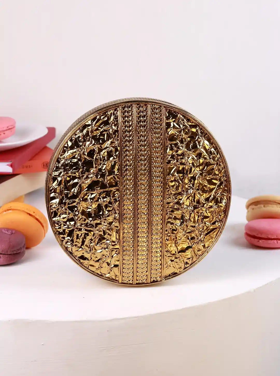 Gold decorative plate with intricate patterns on a white surface with colorful macarons.