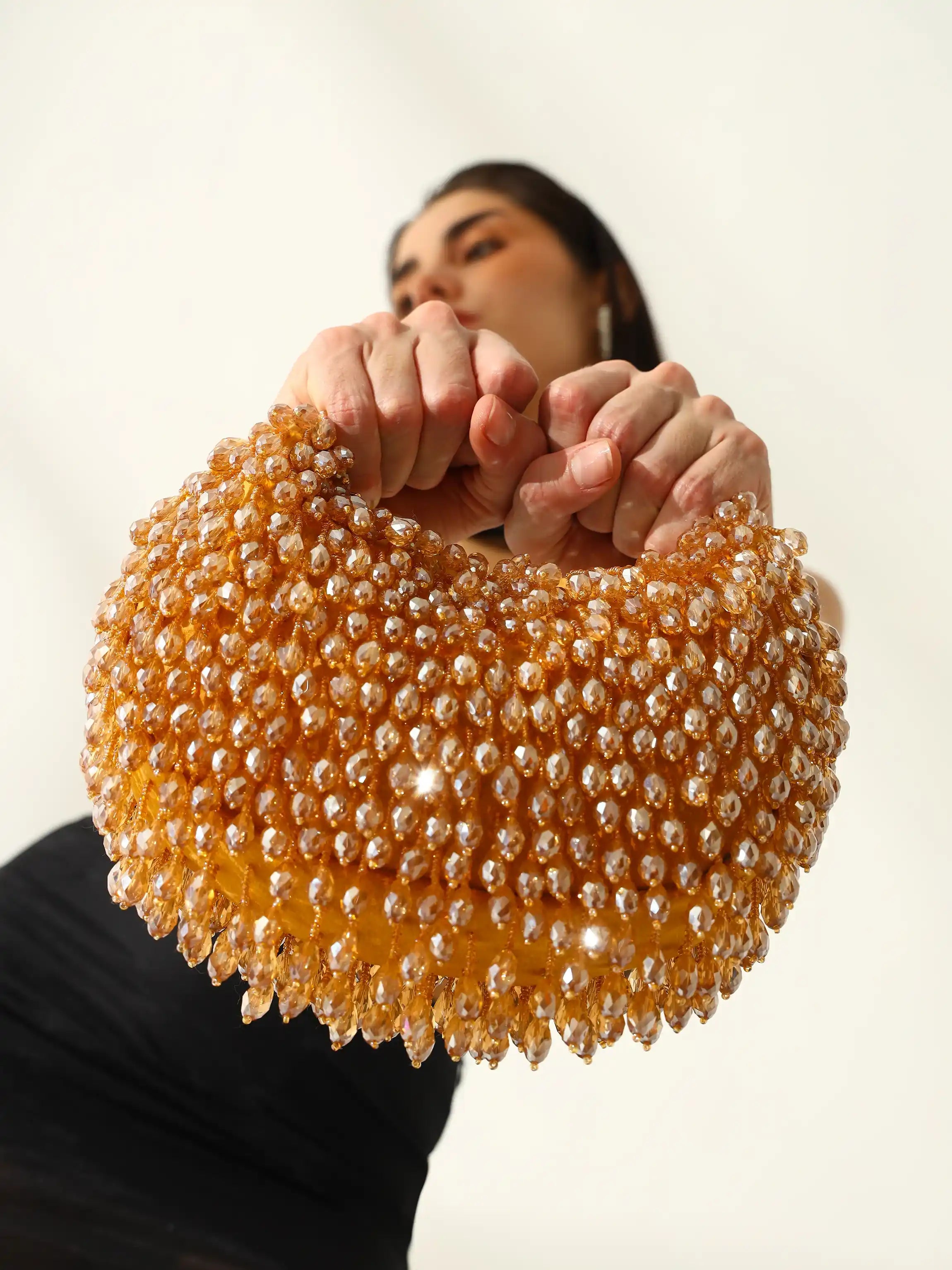 Person holding a beaded handbag against a plain background