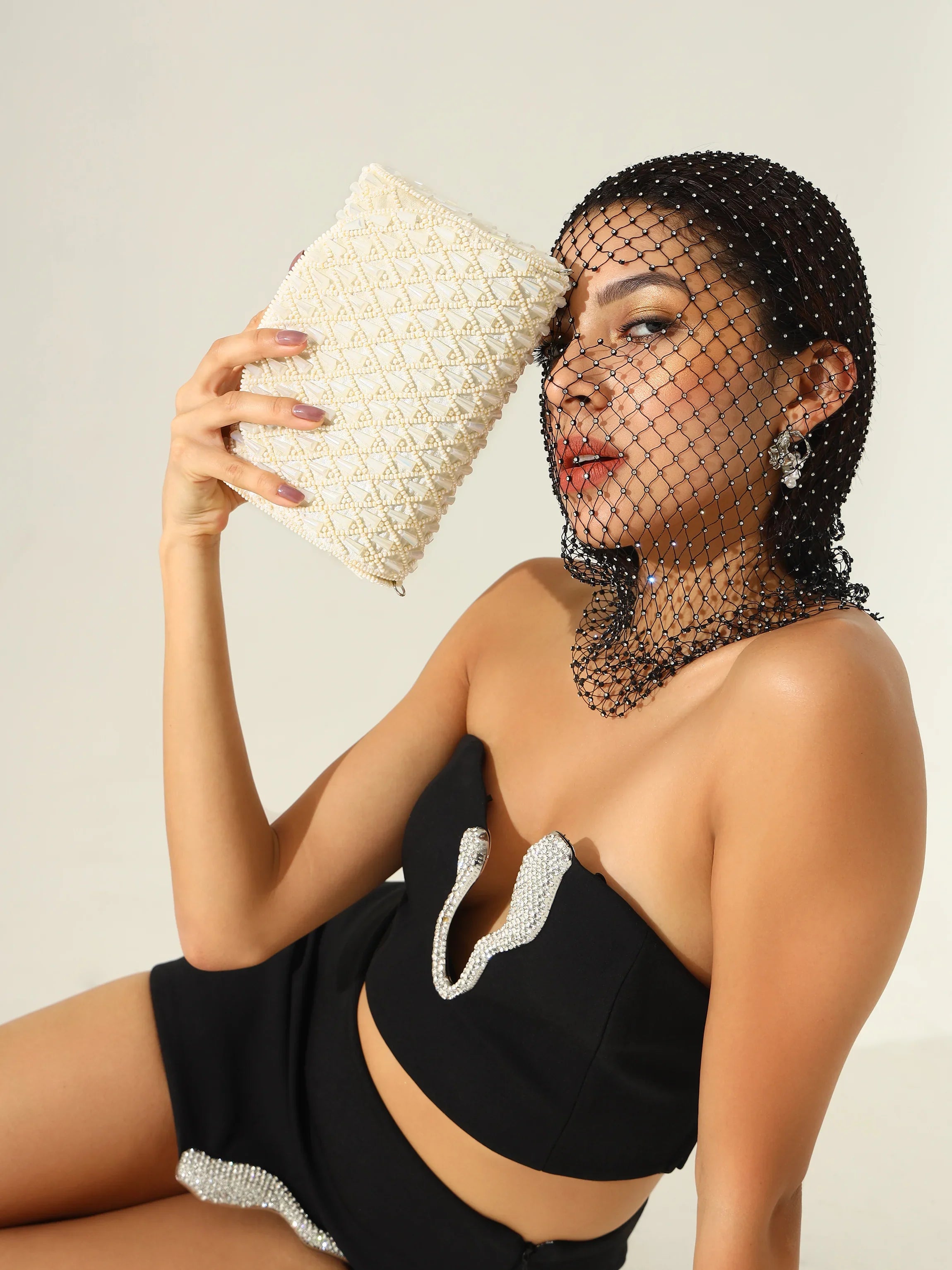 Woman holding a textured clutch against a neutral background