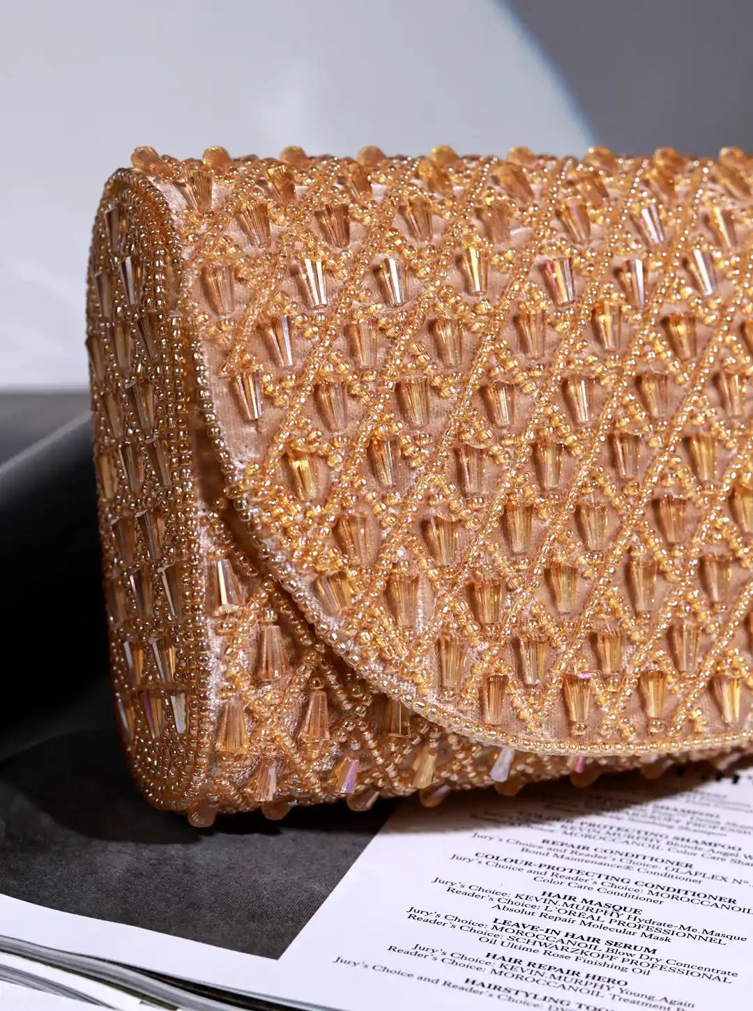 Gold beaded clutch on a magazine with a gray background