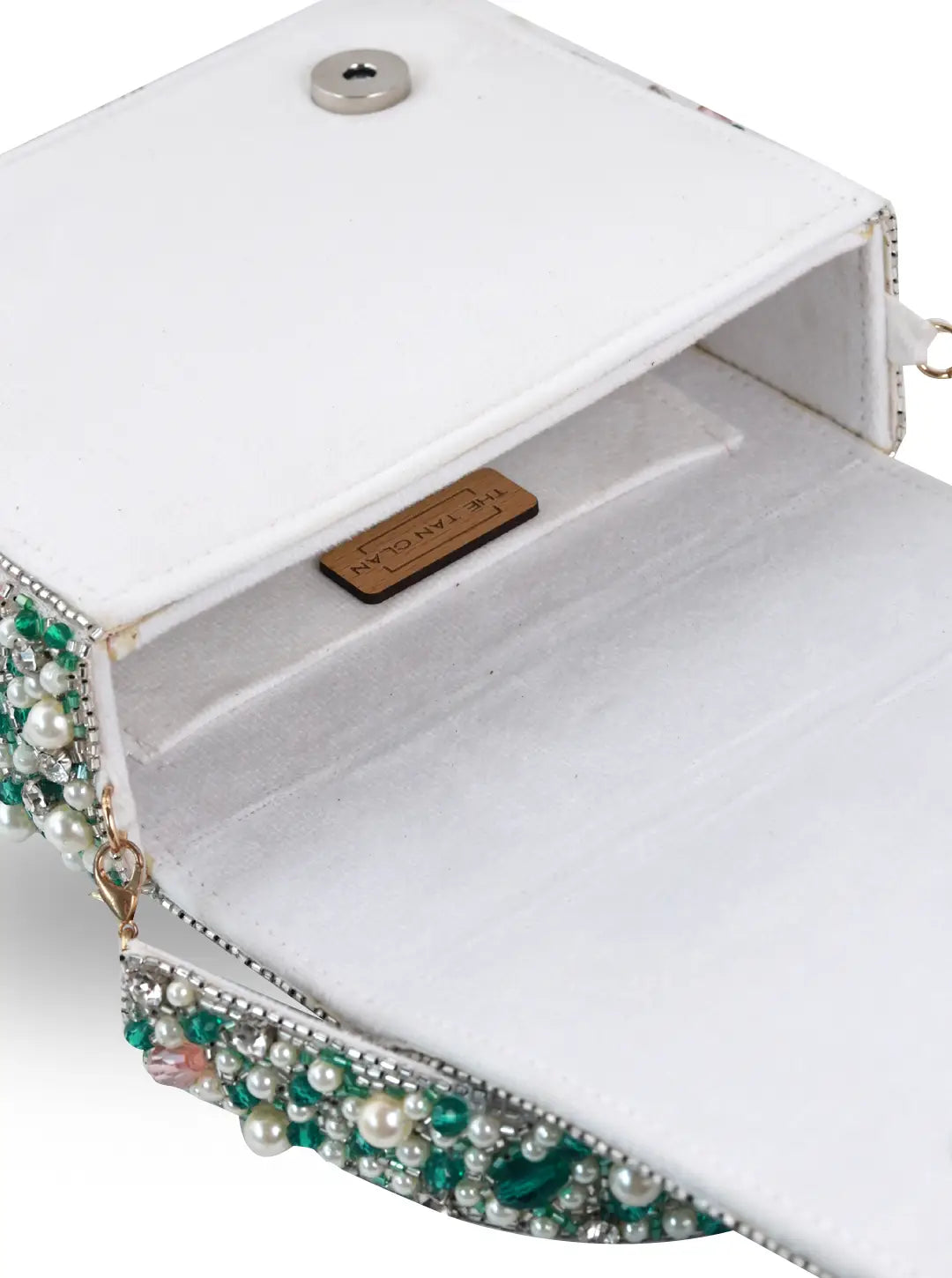 White handbag with decorative gemstones and pearls on a white background