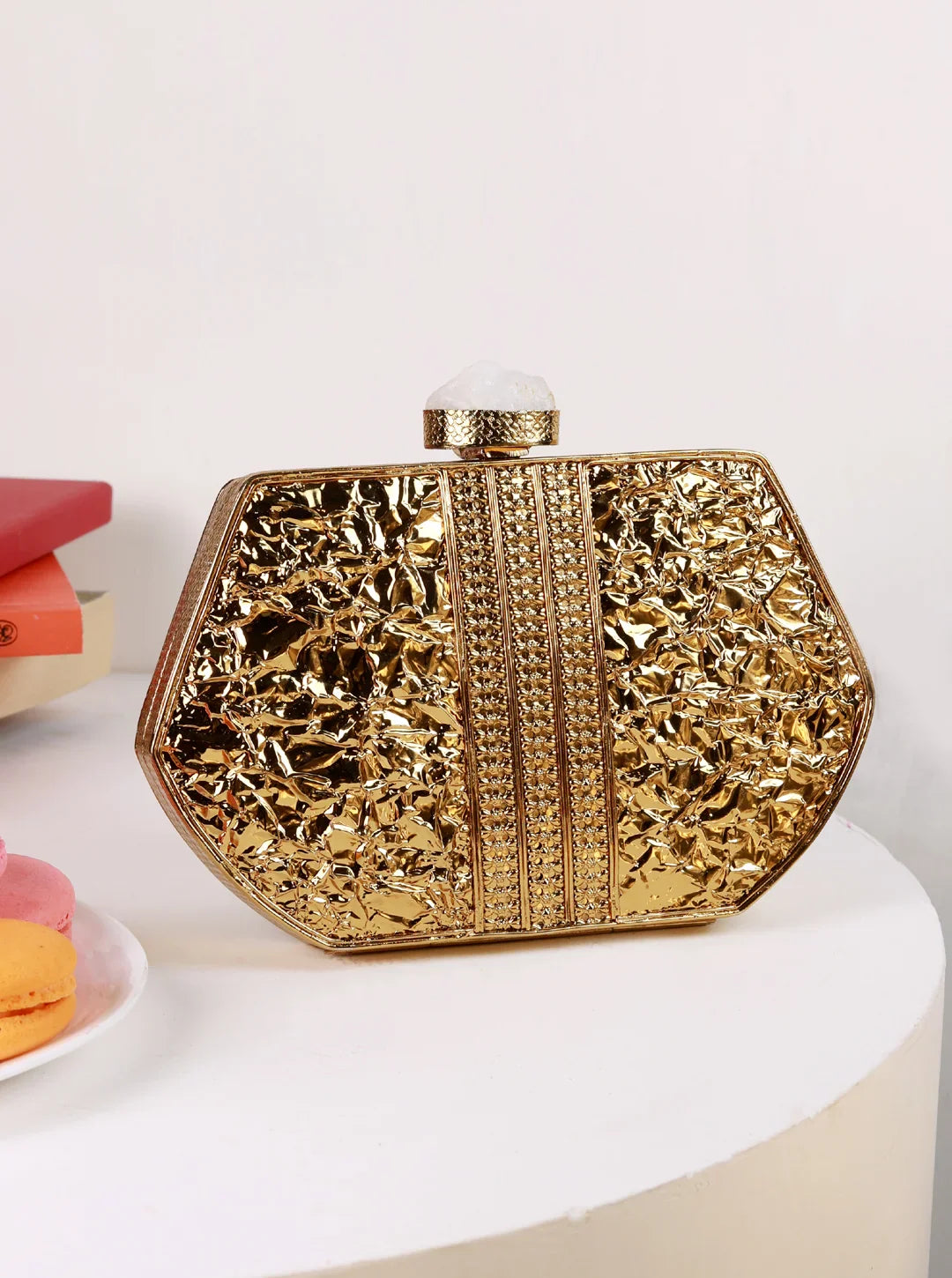 Gold clutch bag with intricate design on a white surface