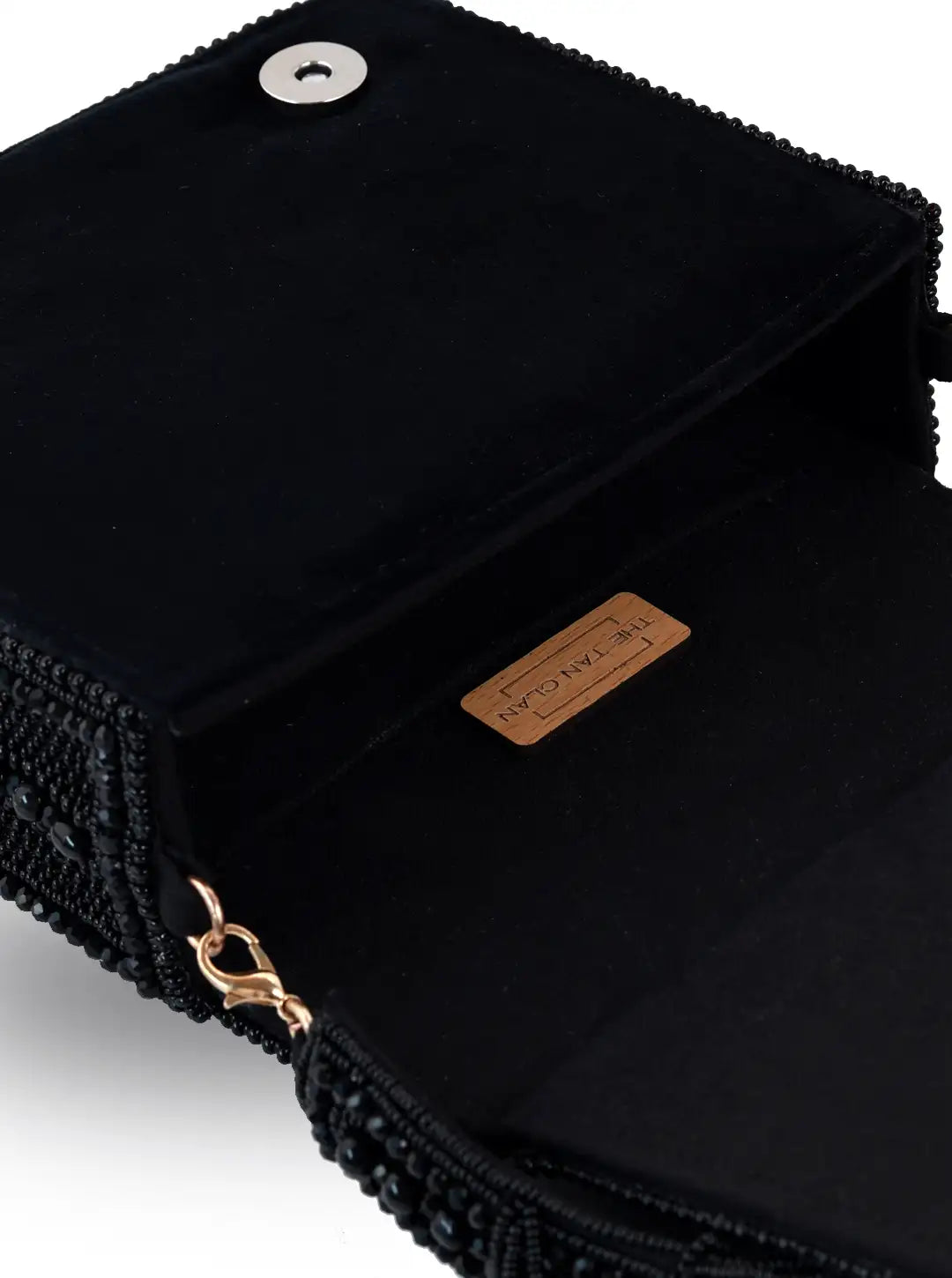 Black textured clutch bag with a brand label on a light gray background