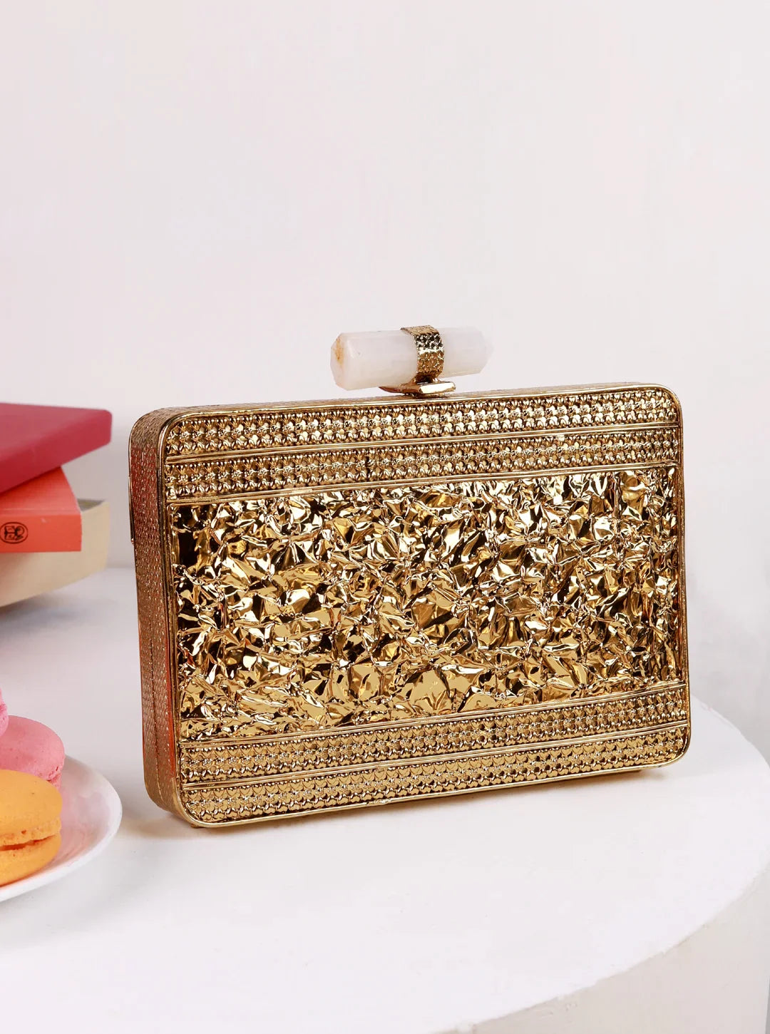 Gold clutch bag with intricate design on a white surface