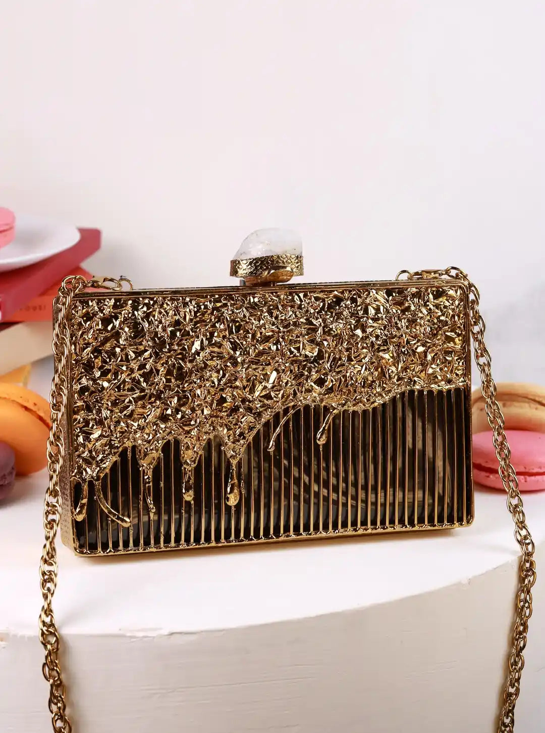 Gold clutch bag with intricate design on a white surface