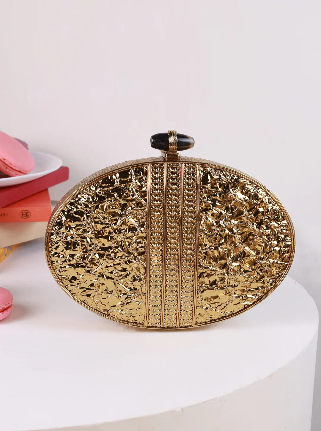 Gold clutch bag with intricate design on a white surface