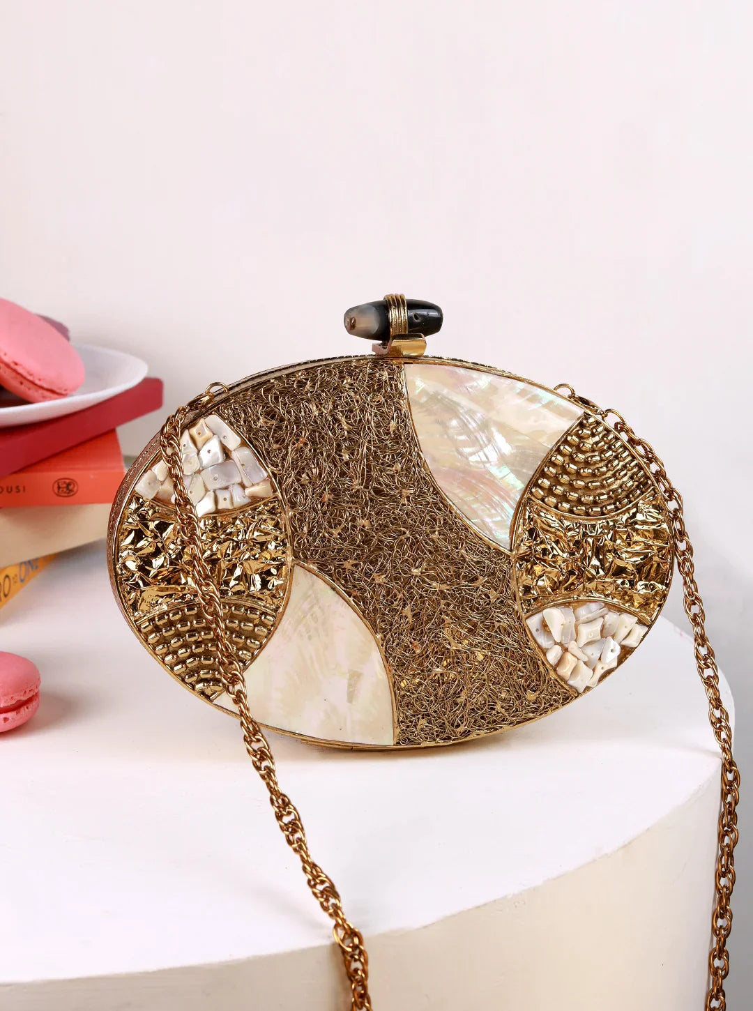 Decorative clutch bag with gold chain on a white surface