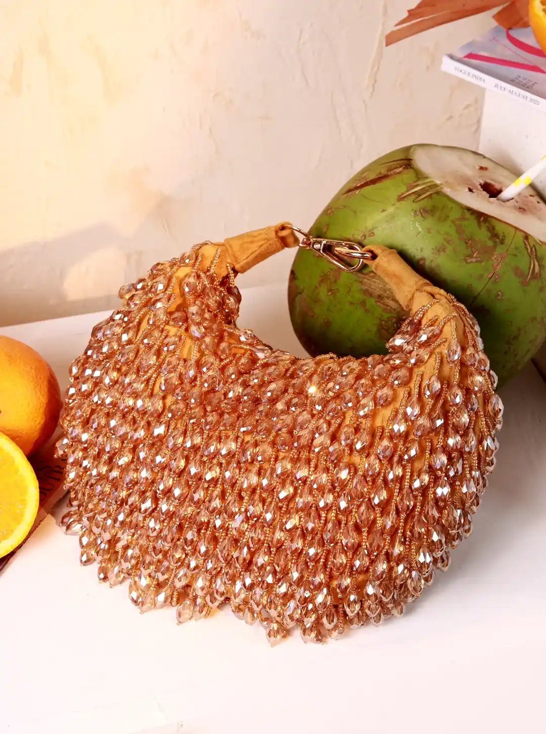 Beaded handbag with a coconut and oranges on a light surface