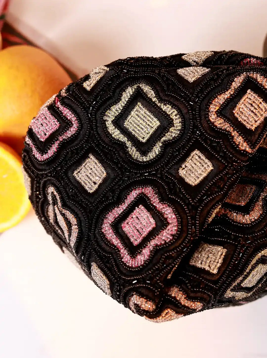 Decorative pillow with geometric pattern on a white surface with oranges in the background