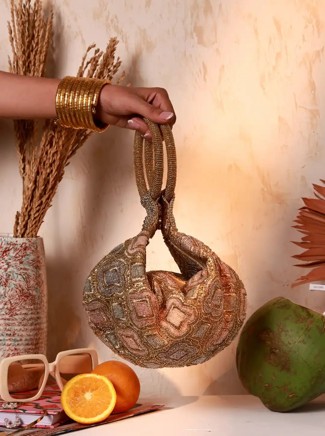Hand holding a textured handbag with decorative elements on a neutral background