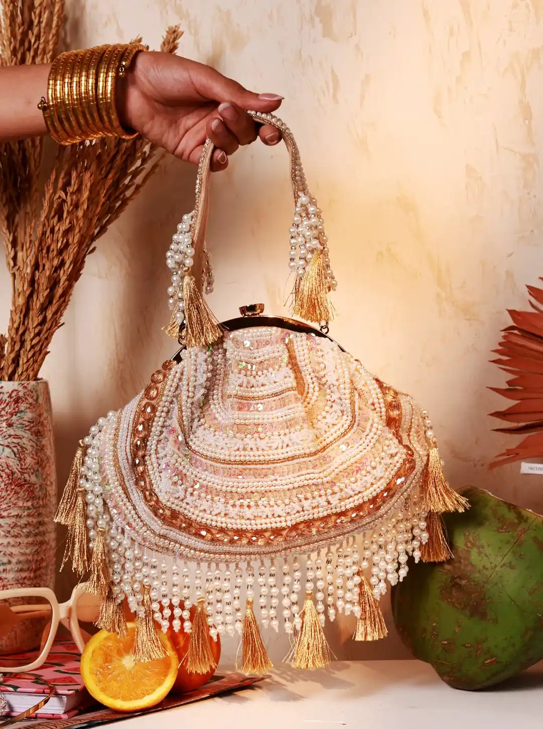 Decorative handbag with beads and tassels held by a hand, with a warm background.