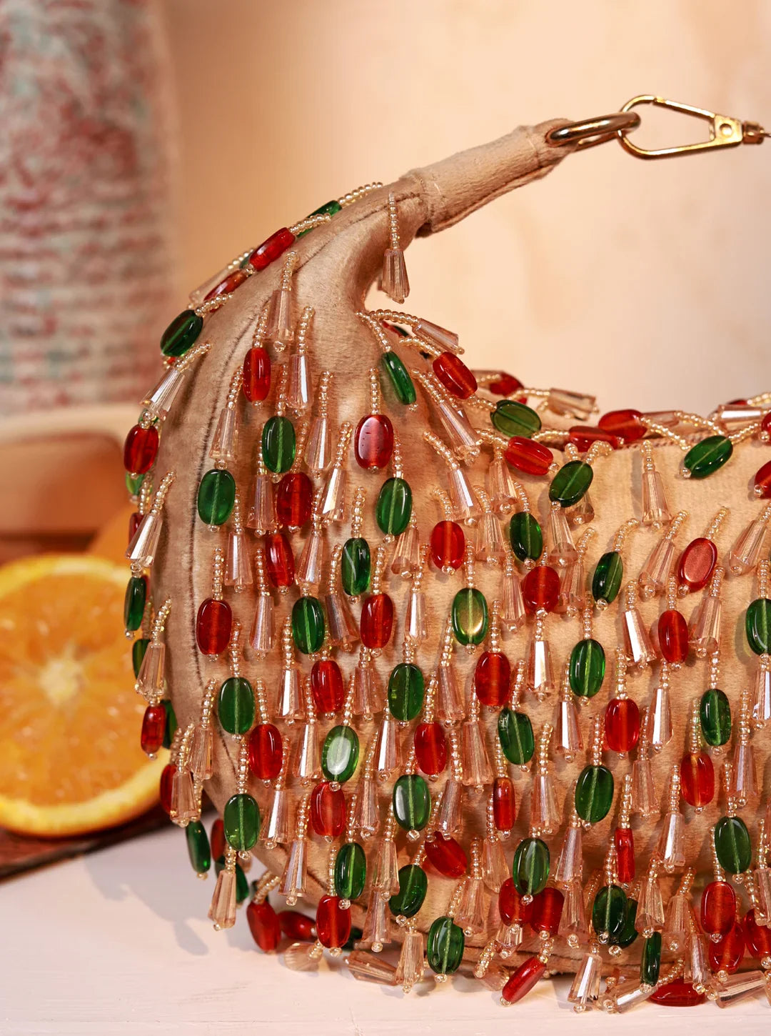 Beaded handbag with red and green accents on a neutral background