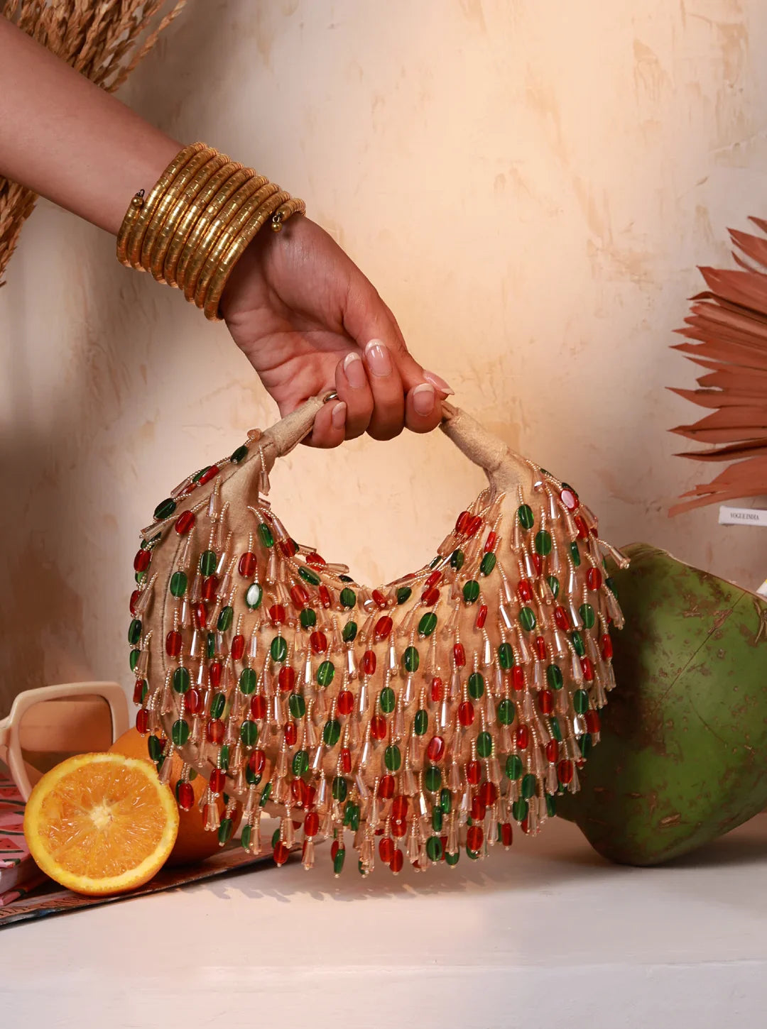 Hand holding a beaded handbag with fruits in the background