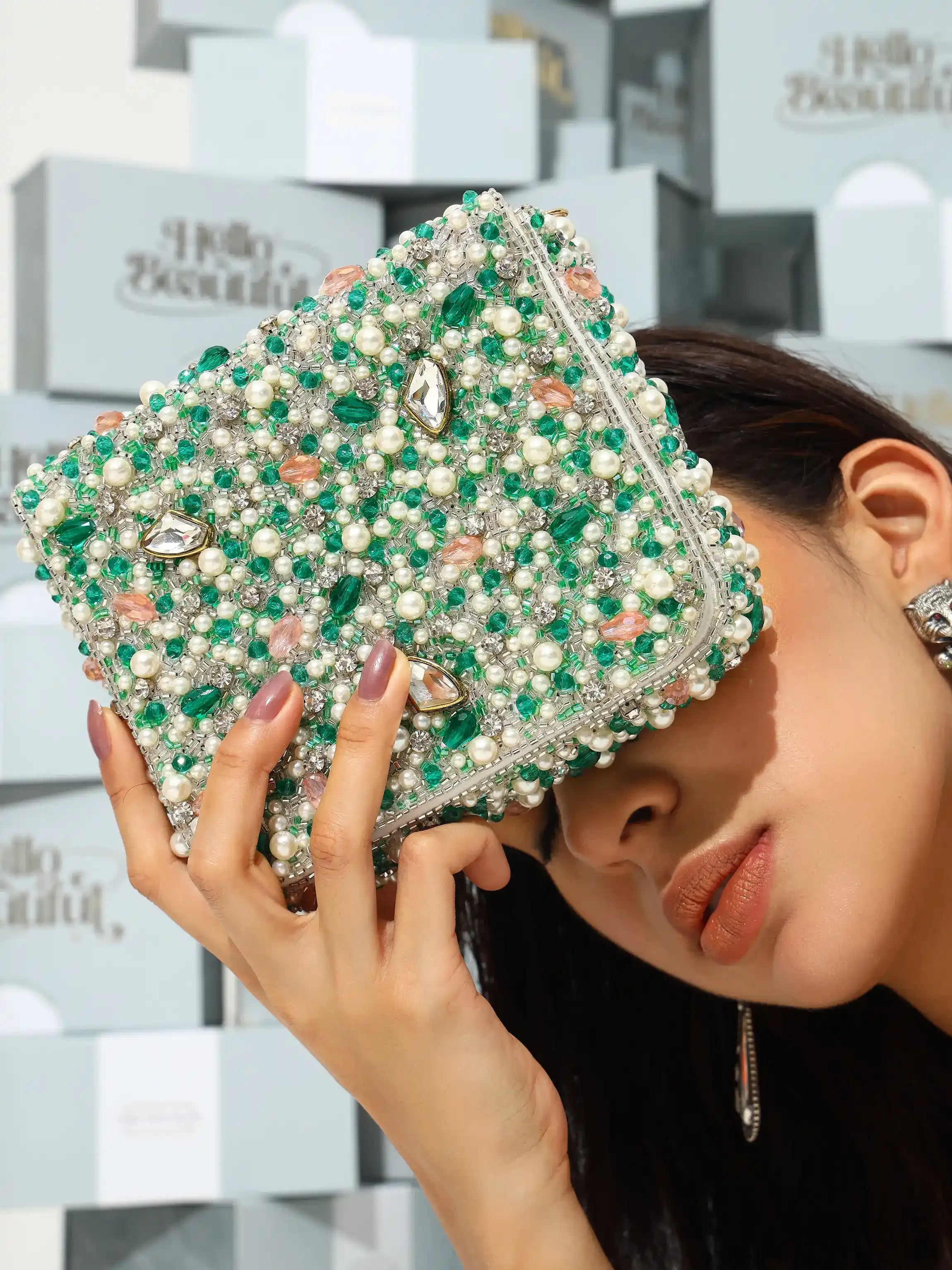 Woman holding a green beaded clutch with blurred background