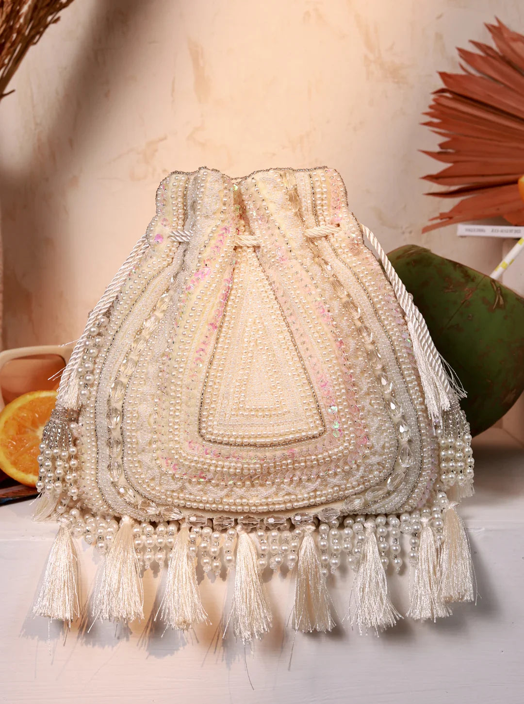 Decorative handbag with beaded details and tassels on a neutral background