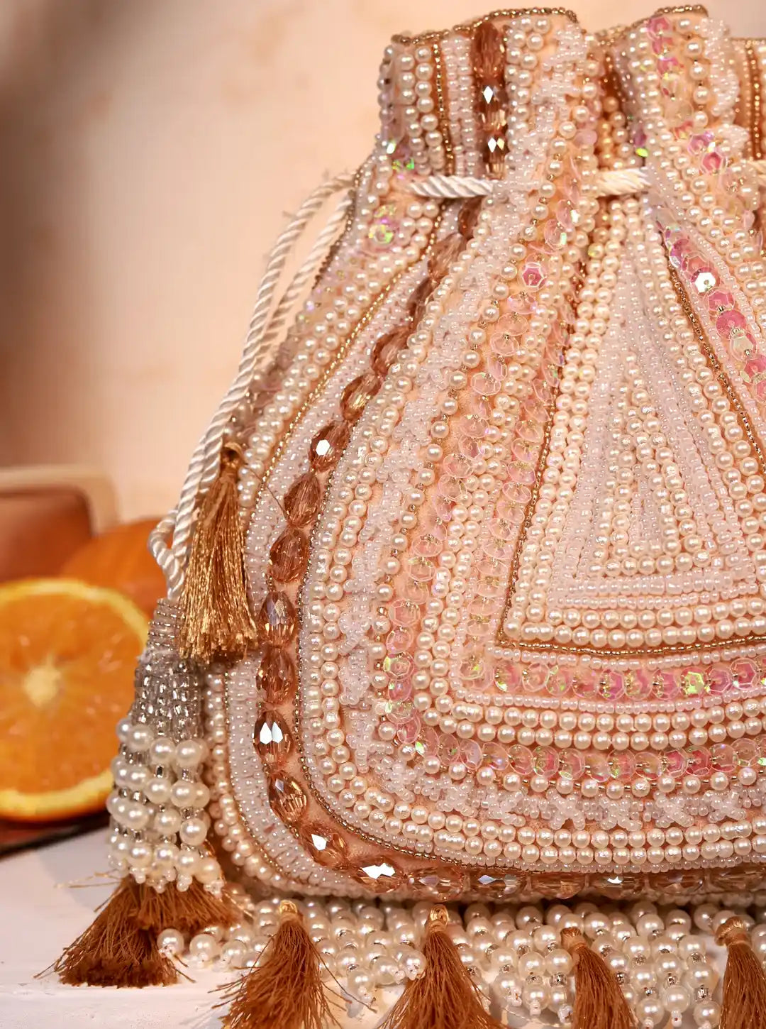 Decorative handbag with intricate beadwork and tassels on a neutral background