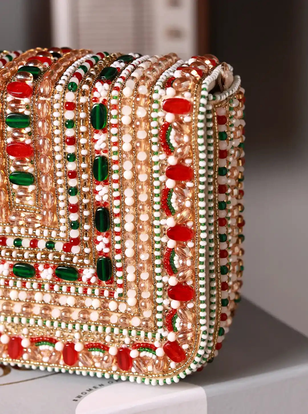 Decorative clutch with red, green, and gold embellishments on a white surface.