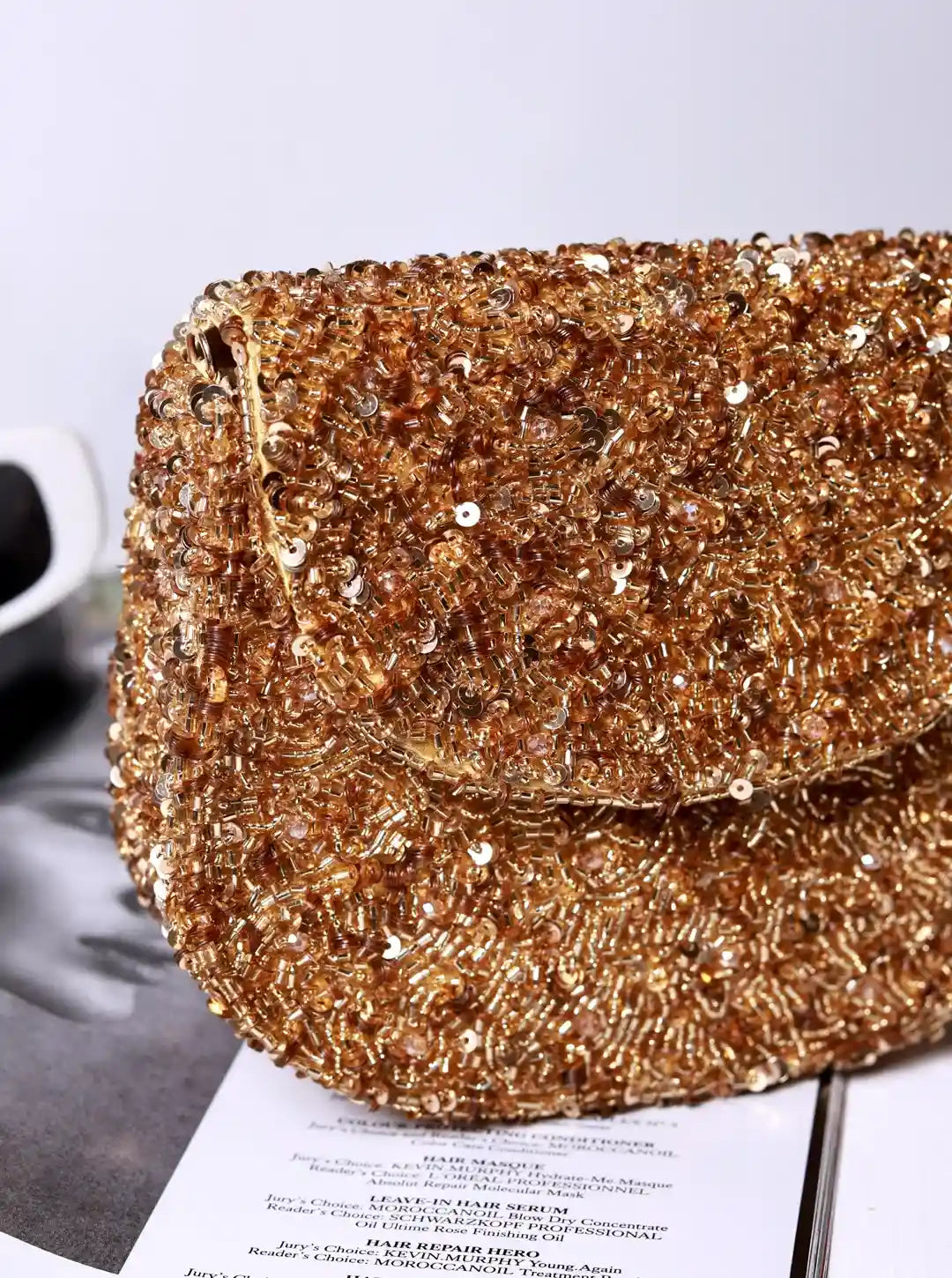 Gold sequin clutch bag on a light gray background