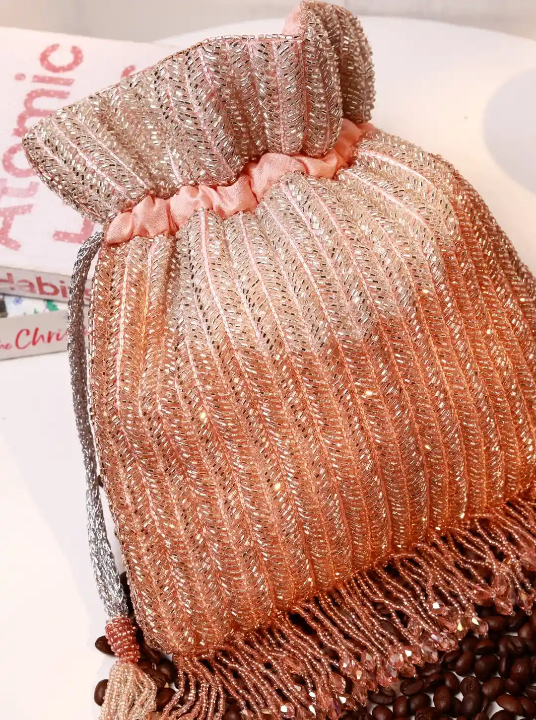 Rose gold handbag with fringe on a white background