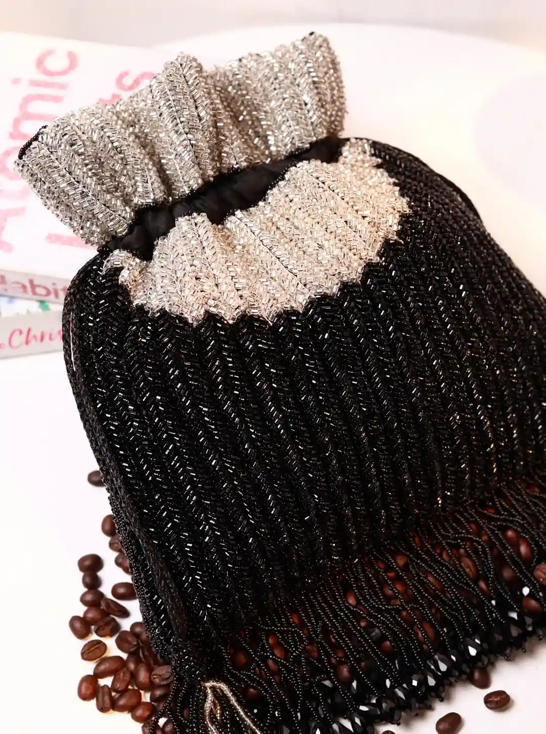 Black beaded handbag with a decorative bow on a white surface