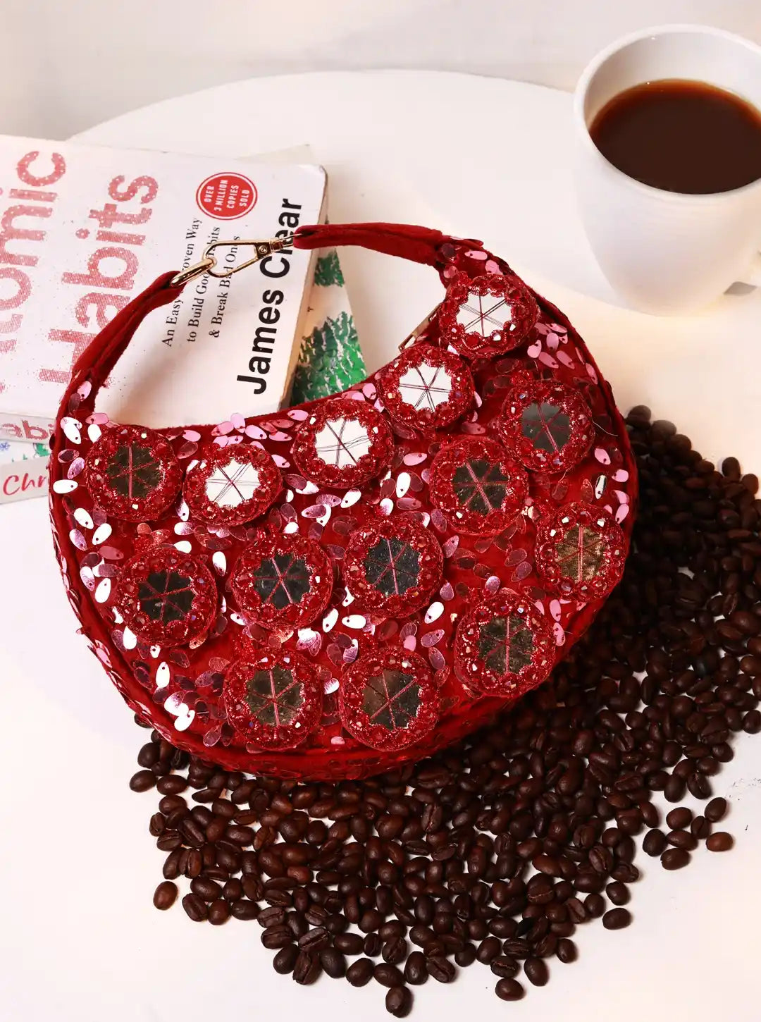Red decorative bag with coffee beans and a cup of coffee on a surface.