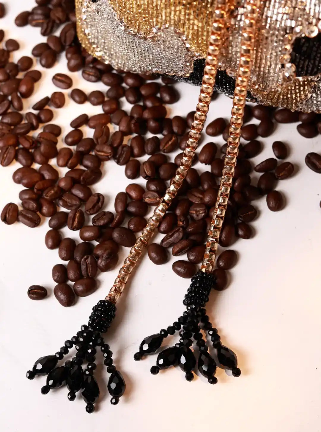Decorative earrings with black beads on a bed of coffee beans