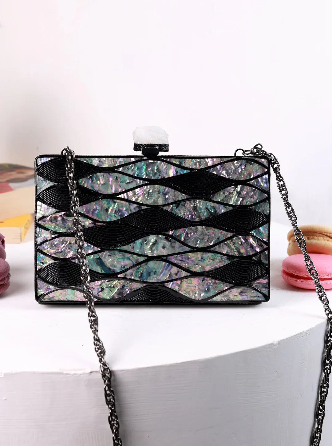 Multicolored handbag with black chain strap on a white surface