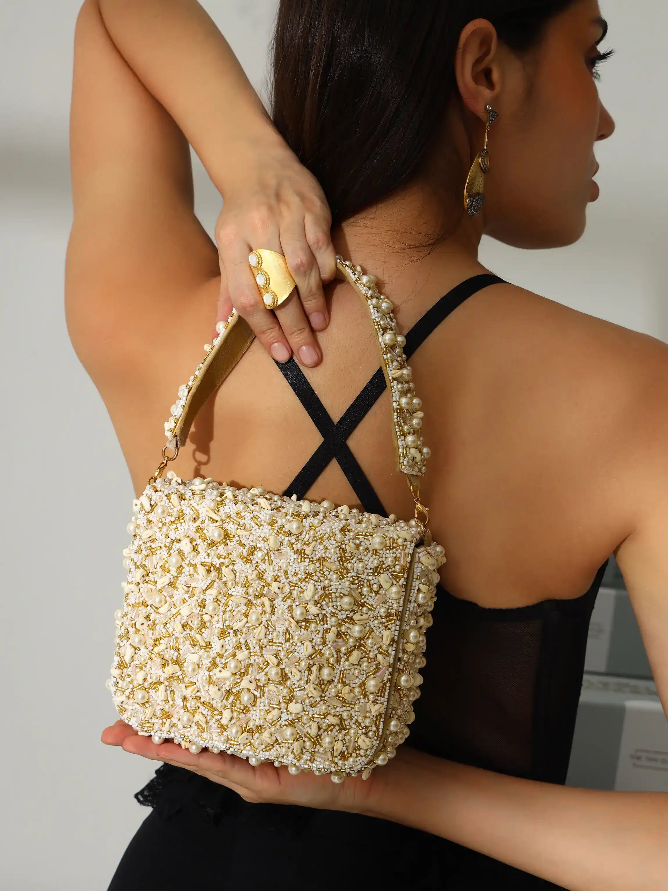 Woman holding a pearl-handled handbag with a plain background