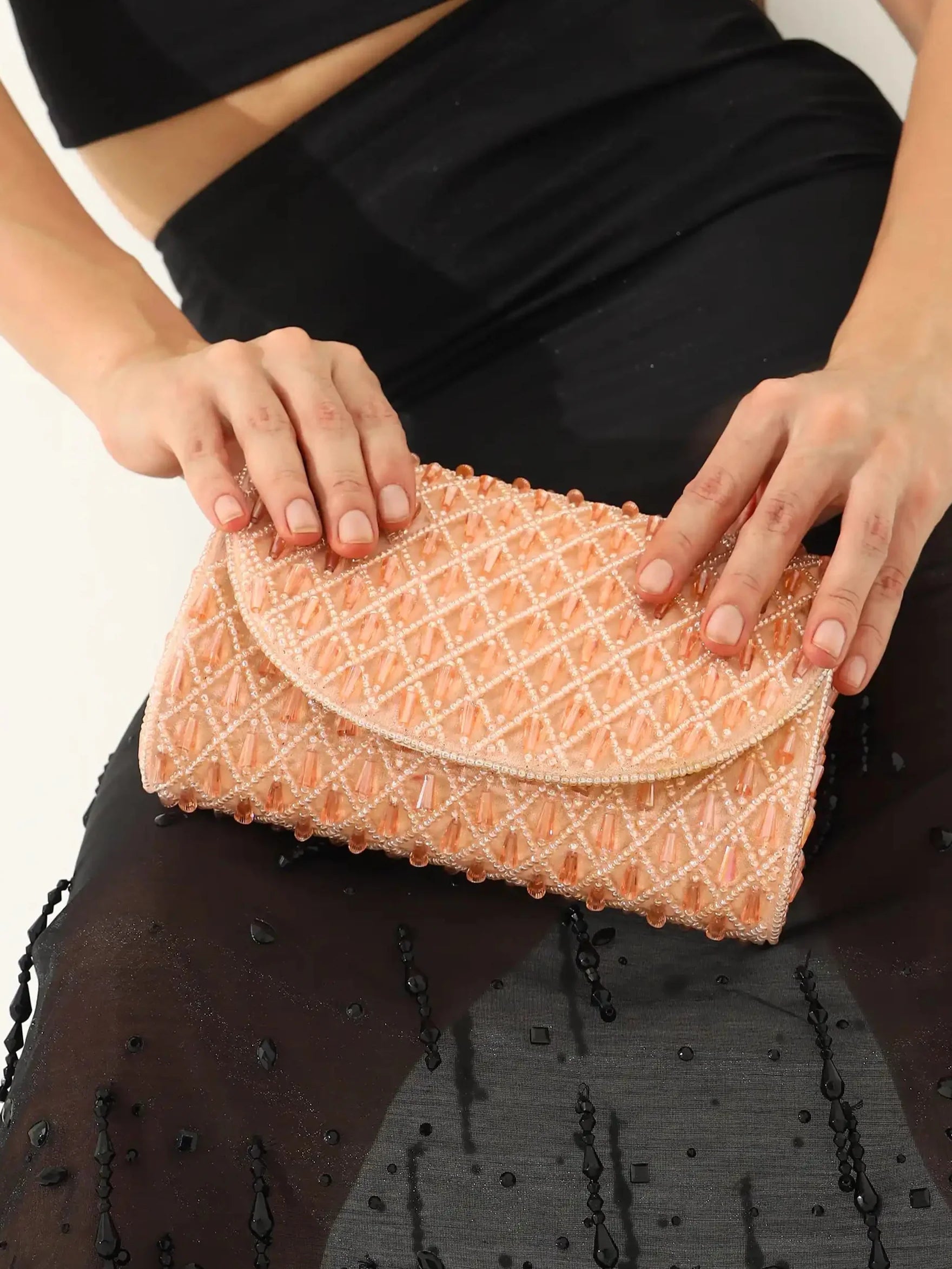 Person holding a patterned clutch bag against a neutral background