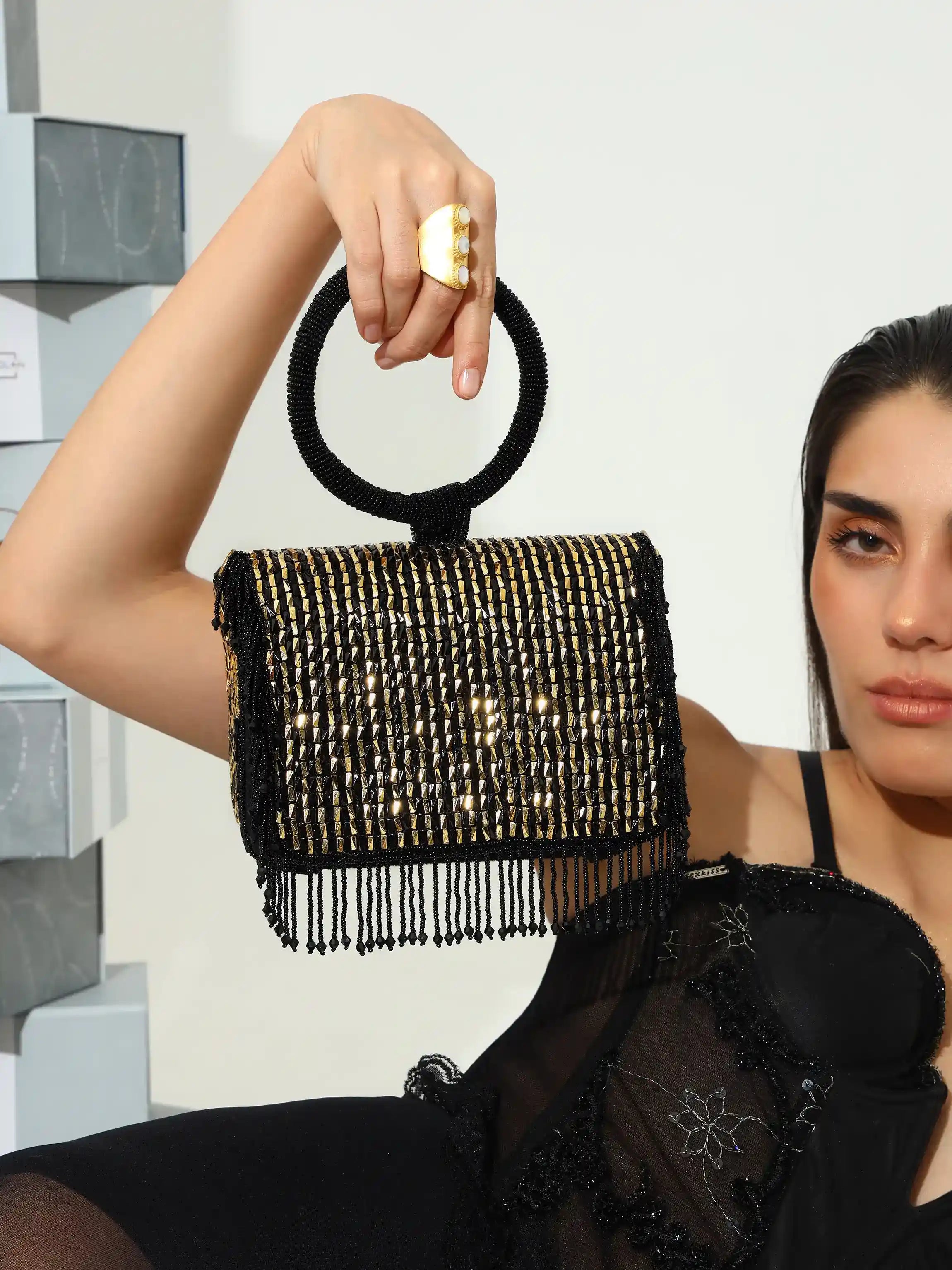 Woman holding a black beaded handbag with a white background