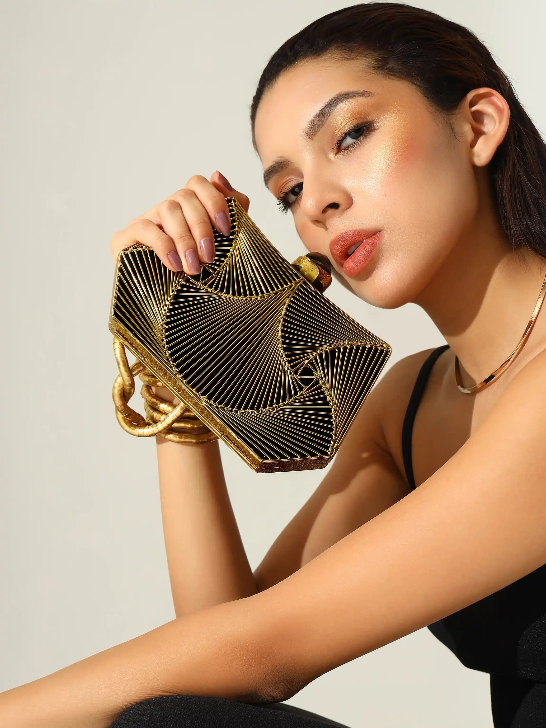 Woman holding a gold handbag against a neutral background