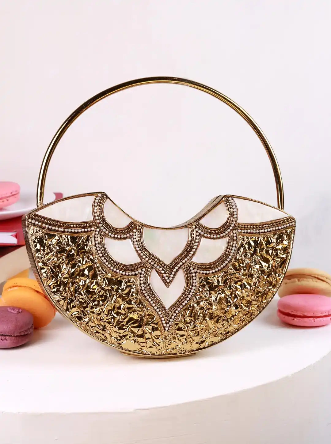 Gold lace handbag with macarons on a white background