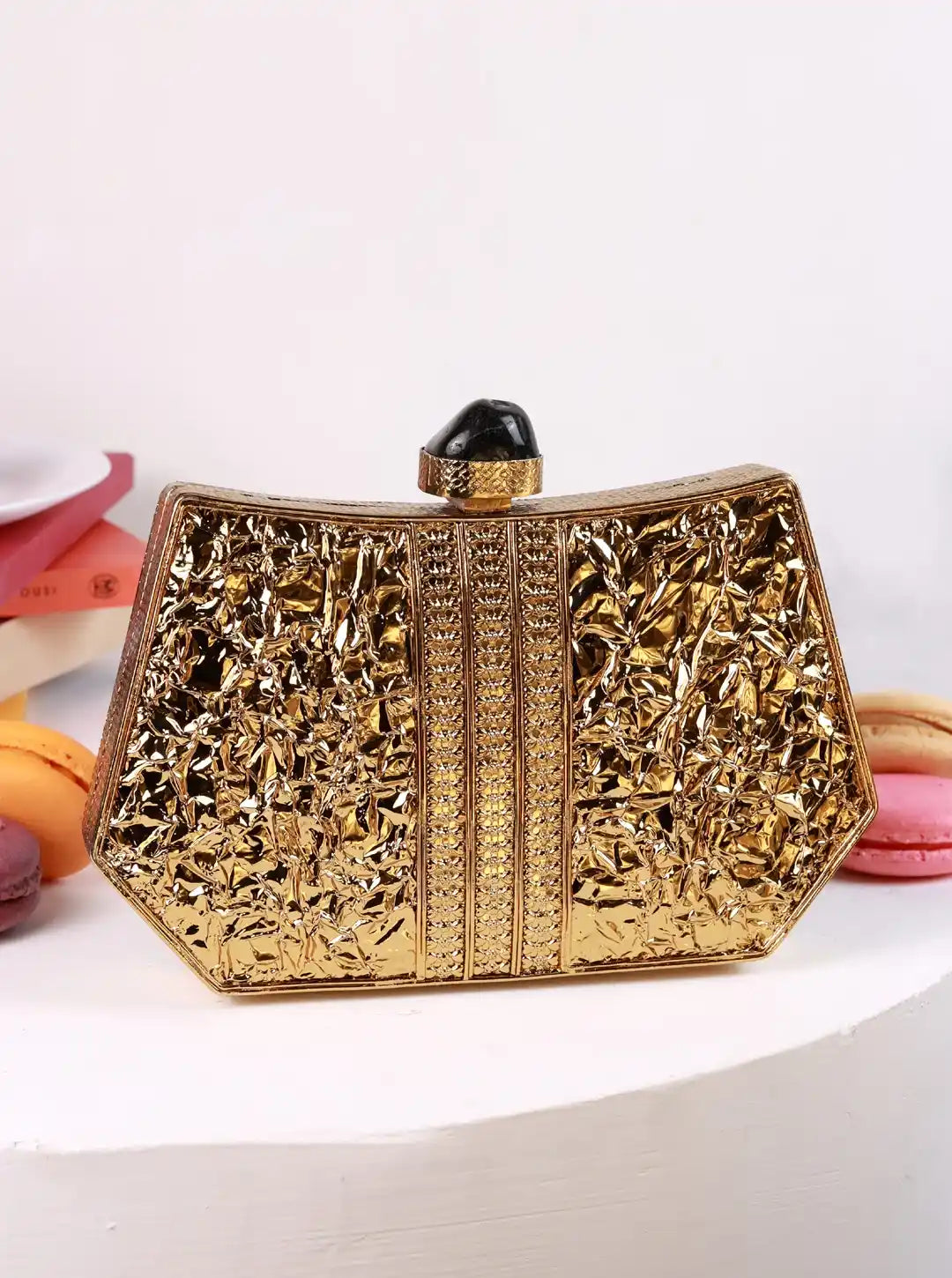 Gold clutch bag with intricate design on a white background